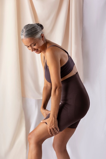 Free photo side view smiley senior woman posing in studio