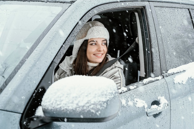 Free photo side view of smiley woman driving the car for on a road trip