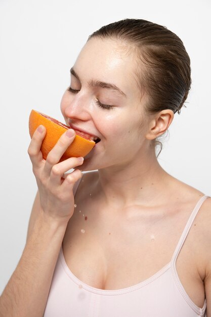 Side view smiley woman eating grapefruit