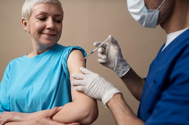 Free photo side view smiley woman getting vaccine