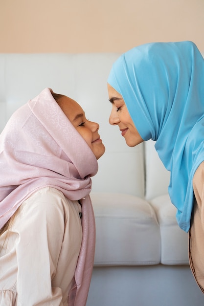 Side view smiley woman and girl with hijabs