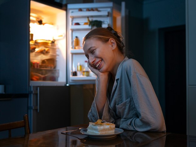 Side view smiley woman having snacks at night