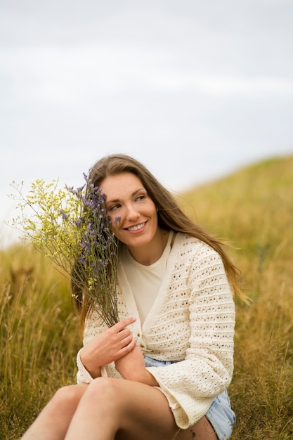 Side view smiley woman holding flowers