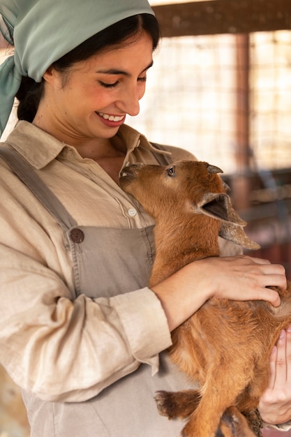 Free Photo side view smiley woman holding goat