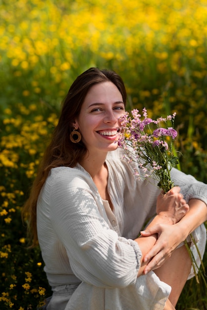 Side view smiley woman holding purple flowers