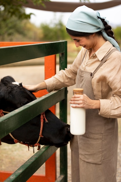 Free Photo side view smiley woman petting cow