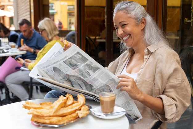 Side view smiley woman reading the newspaper