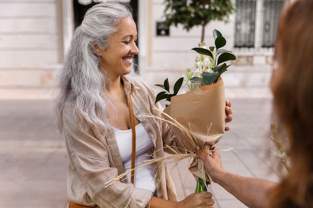 Side view smiley woman receiving flowers