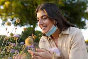 Free photo side view smiley woman smelling flowers