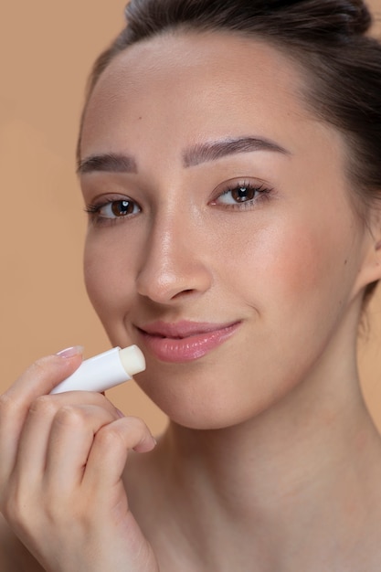 Side view smiley woman using lip balm