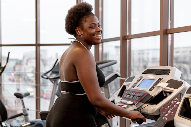 Side view smiley woman working on treadmill