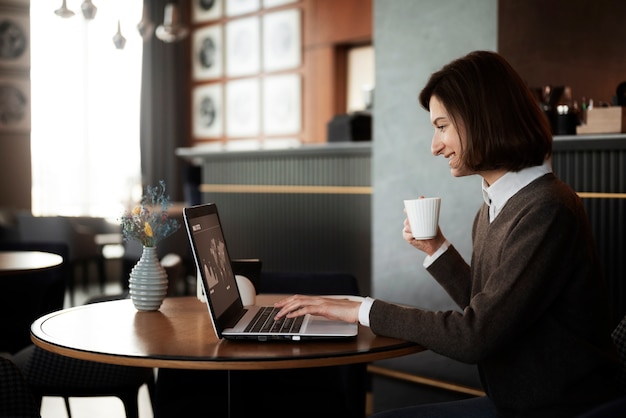 Side view smiley woman working with laptop