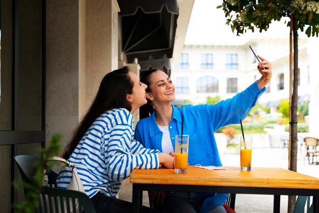 Side view smiley women taking selfie outdoors