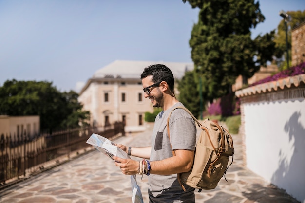 Free photo side view of smiling man looking at map standing on street