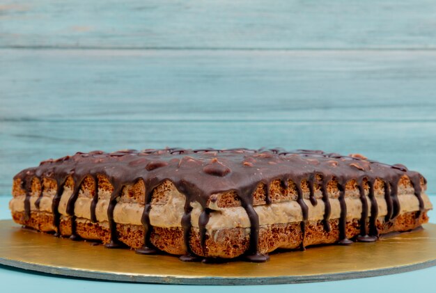 Side view of snickers cake on blue surface with copy space