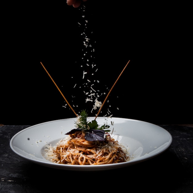 Side view spaghetti with greens and ricotta cheese in round white plate