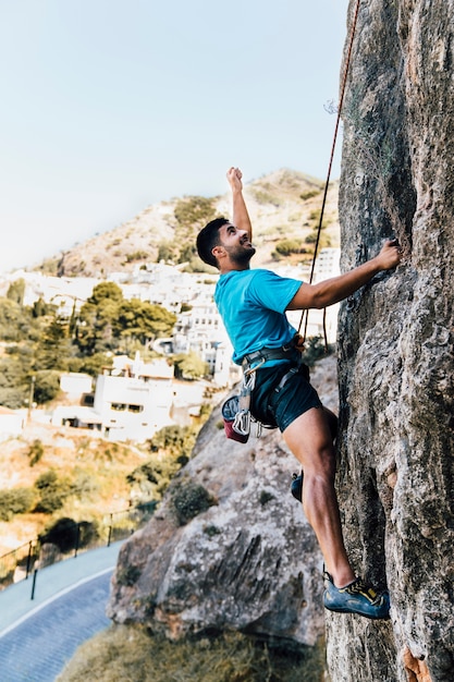 Side view of sporty man climbing on rock