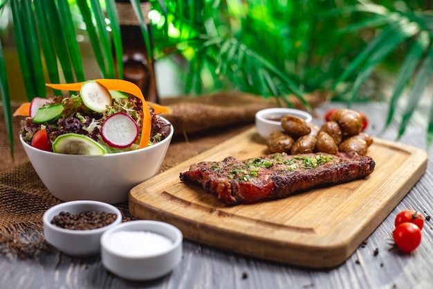 Side view steak with baked potatoes and vegetable salad