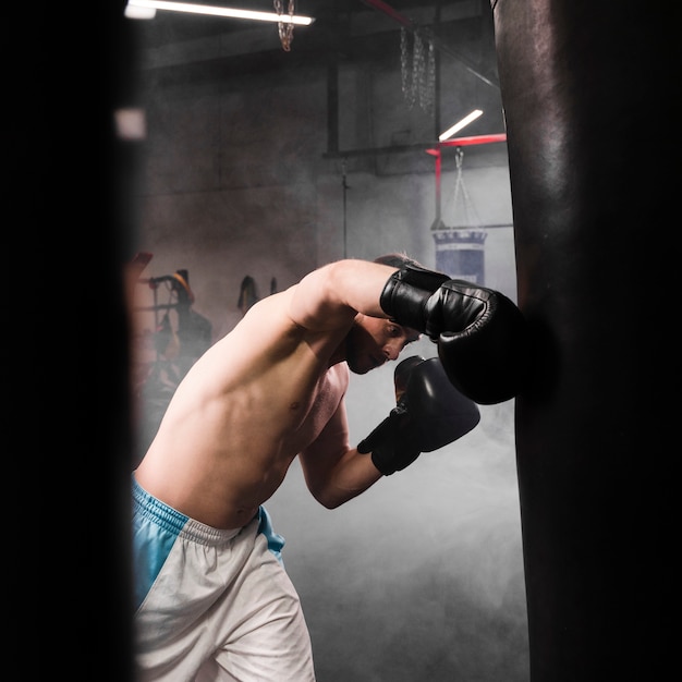 Free photo side view strong male boxer training for a competition