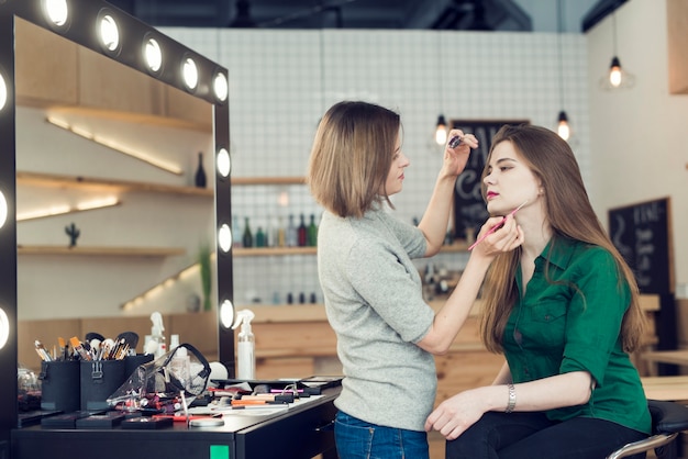 Side view stylist with eyeliner working with model