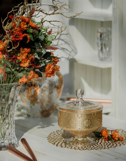 Side view of sugar-bowl with flowers in a vase on wall