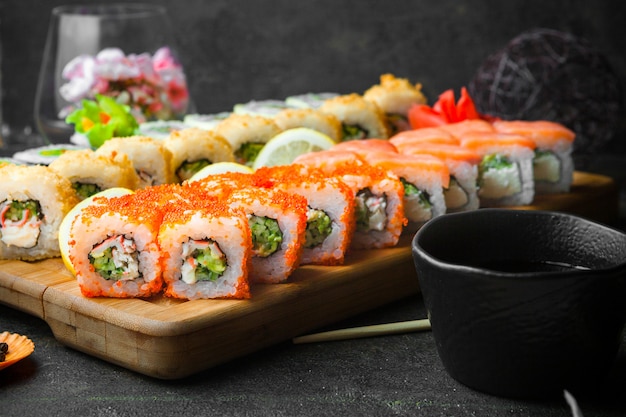 Side view sushi set with soy sauce and chopsticks in wooden serving board