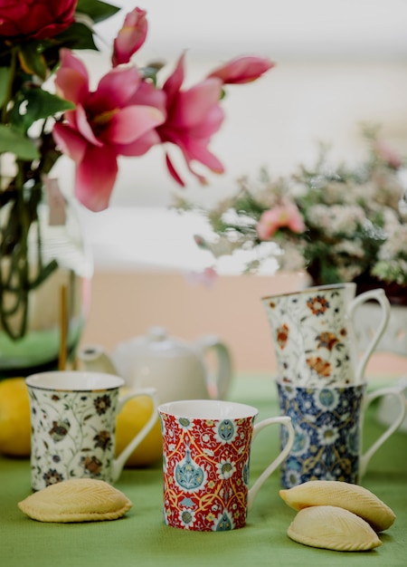 Side view of tea cups with oriental pattern and traditional azerbaijani sweetness shekerbura on floral wall