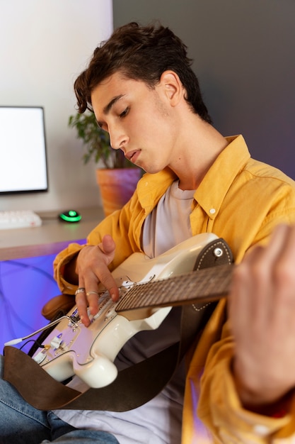 Free photo side view teen playing the guitar at home