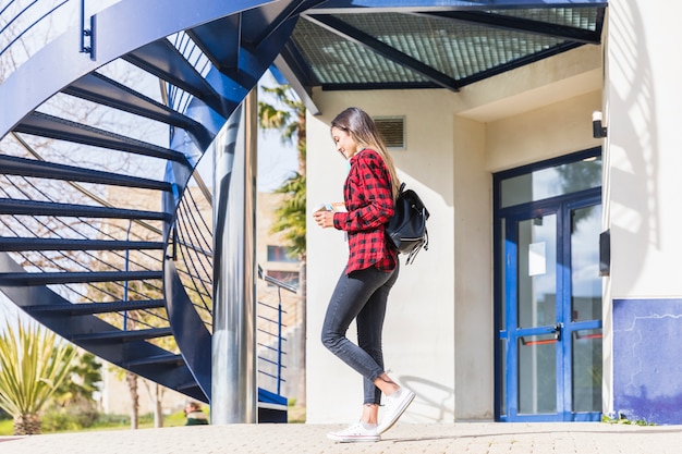 Free photo side view of a teenage female student walking in front of university building