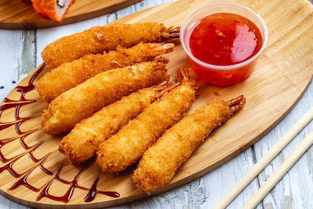 Free photo side view tempura shrimps with sweet chili sauce on a board