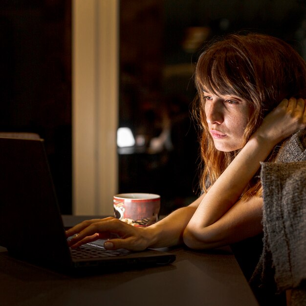 Side view tired woman with laptop indoors