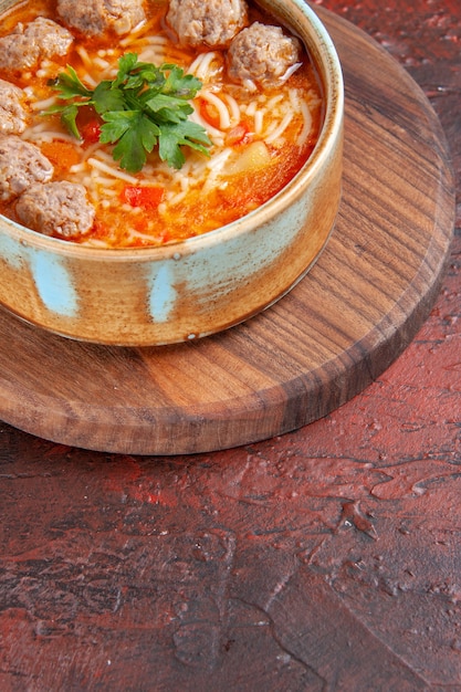 Free Photo side view of tomato meatballs soup with noodles in a brown bowl on dark background vertical view