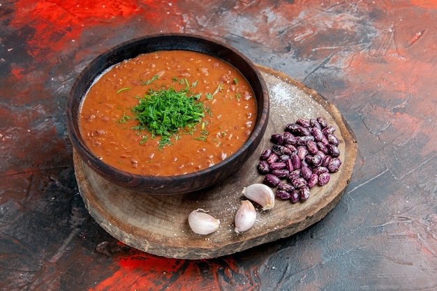 Side view of tomato soup beans garlic on wooden cutting board on mix color table