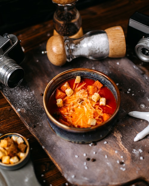 Side view of tomato soup with cheese and toasts in bowl