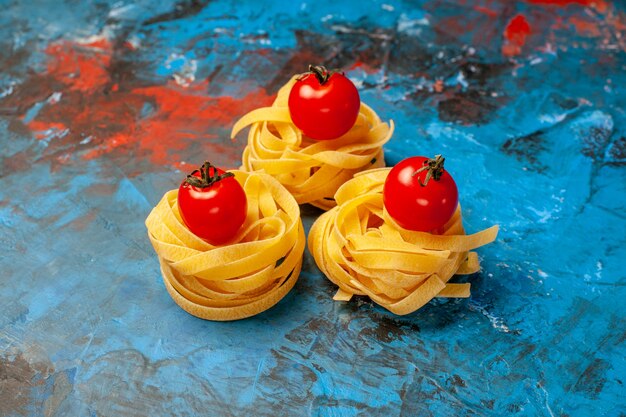 Side view of tomatoes on homemade pastas on blue background