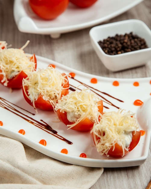 Free Photo side view of tomatoes stuffed with cheese on a wooden table