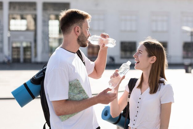 Side view of tourist couple staying hydrated outdoors