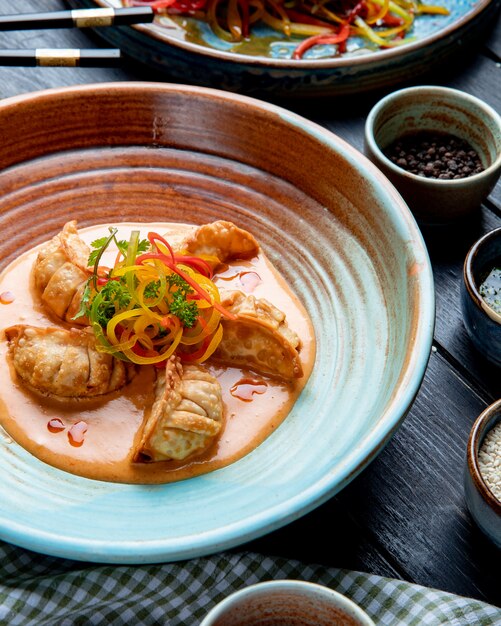 Side view of traditional asian dumplings with meat and vegetables served with sauce on a plate on rustic