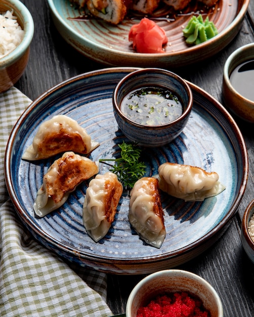 Side view of traditional asian dumplings with meat and vegetables served with soy sauce on a plate on rustic