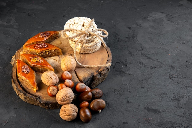 Side view of traditional azerbaijani baklava with nuts rice breads on wooden board on black