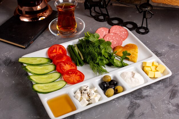 Side view of traditional turkish breakfast with olives feta cheese honey vegetables and tea