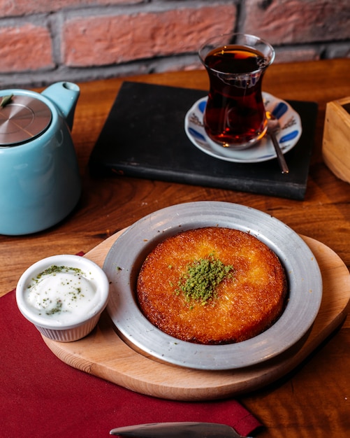 Side view of traditional turkish dessert kunefe with pistachio powder and cheese on a wooden table