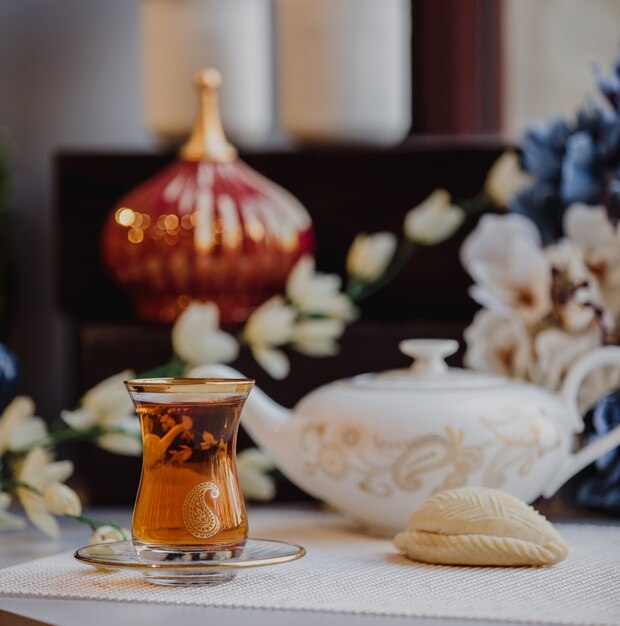 Side view of turkish azeri traditional pear-shaped glass for black tea armudu with shekerbura on the table