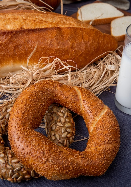 Side view of turkish bagels with baguette on straw on maroon surface