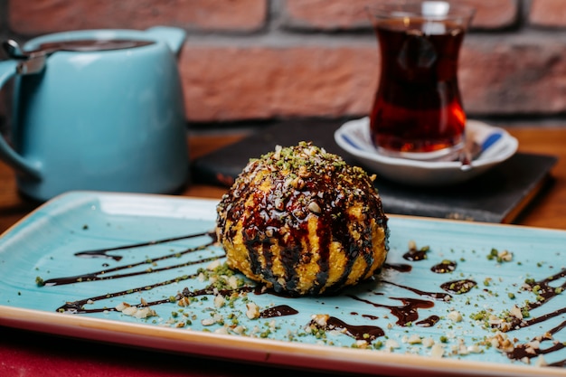 Free photo side view of turkish dessert fried ice-cream covered with chocolate syrup on the table