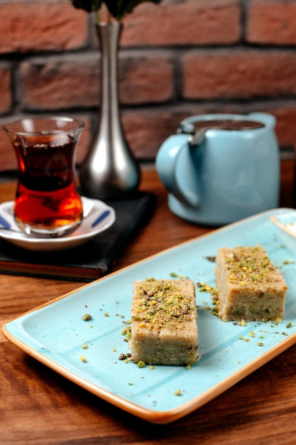 Free photo side view of turkish sweets baklava with pistachio served with ice cream on platter