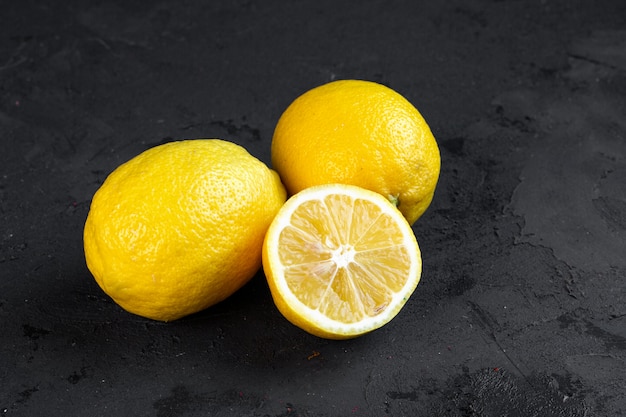 Free photo side view two whole lemons with a slice of chopped lemon