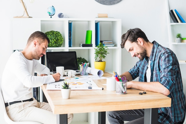 Side view of two young businessmen sitting in office