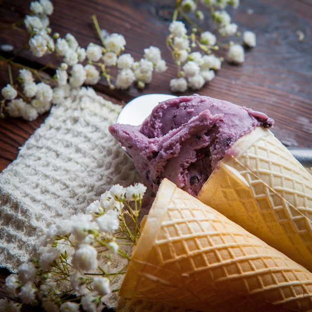 Side view waffle cones with blueberry ice cream and gypsophila in rag napkins