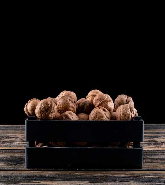 Free Photo side view walnuts in black box on wooden horizontal